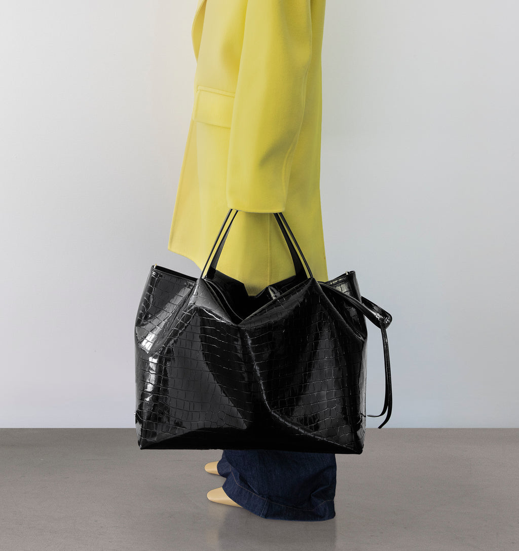 Model carrying the LA MAMA LM1 handbag in Black Lacquer Croco in hand.