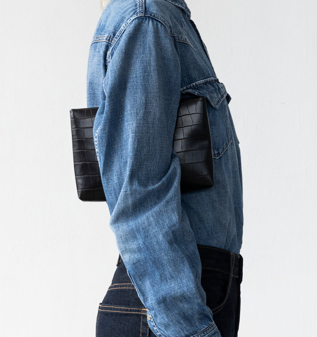 Model carrying the Small Pouch in Black Matte Croco under arm.