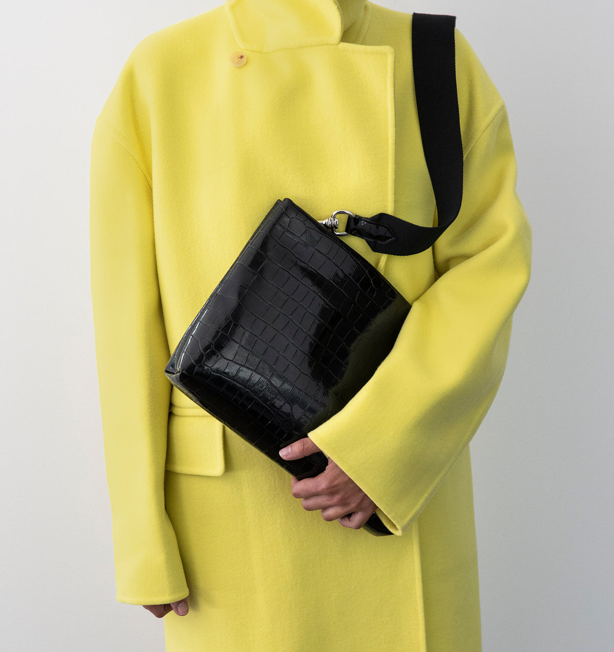 Model wearing the Large Pouch in Black Lacquer Croco over the shoulder with the Tracolla.