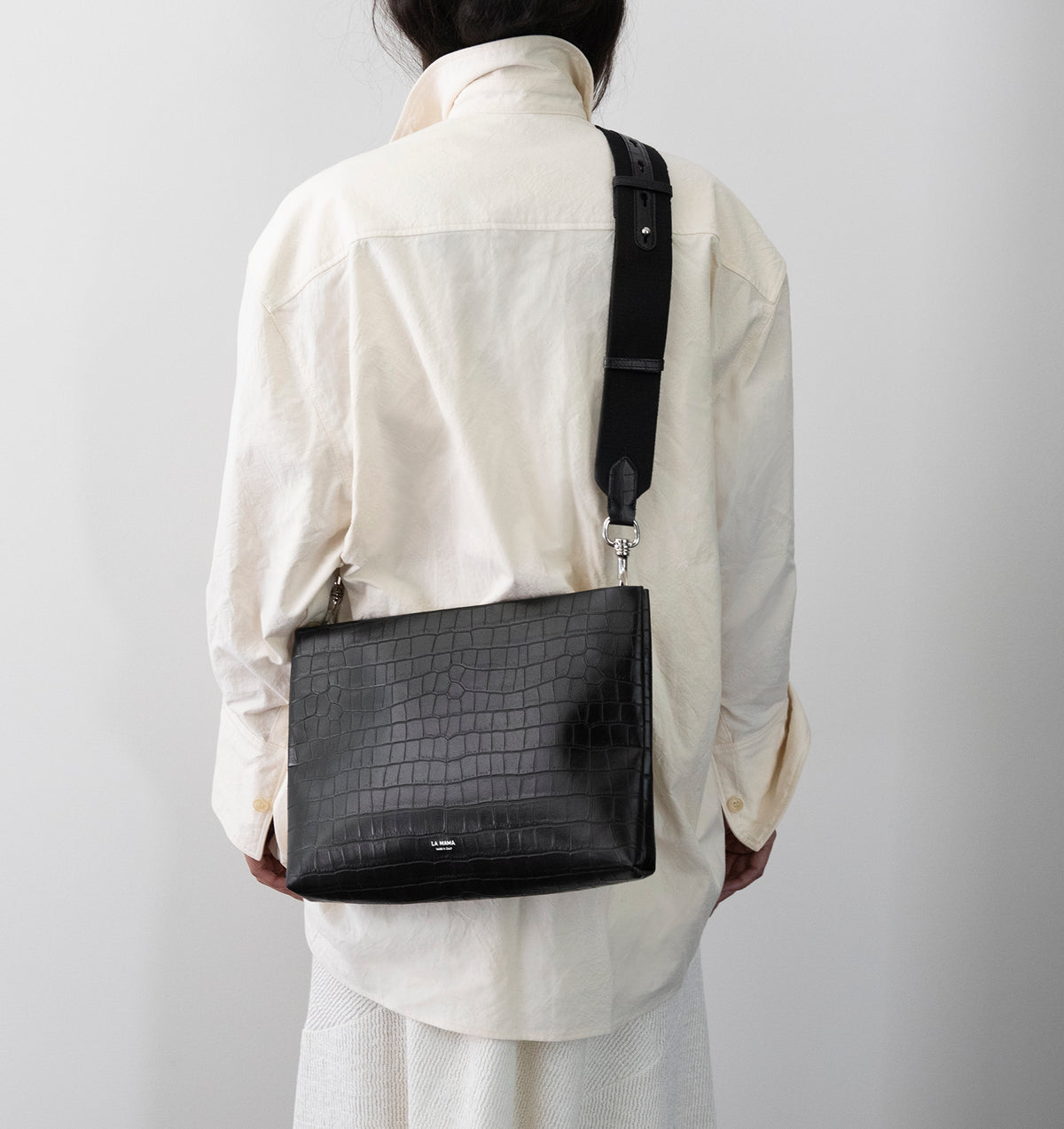Model wearing the Large Pouch in Black Matte Croco crossbody with the Tracolla.
