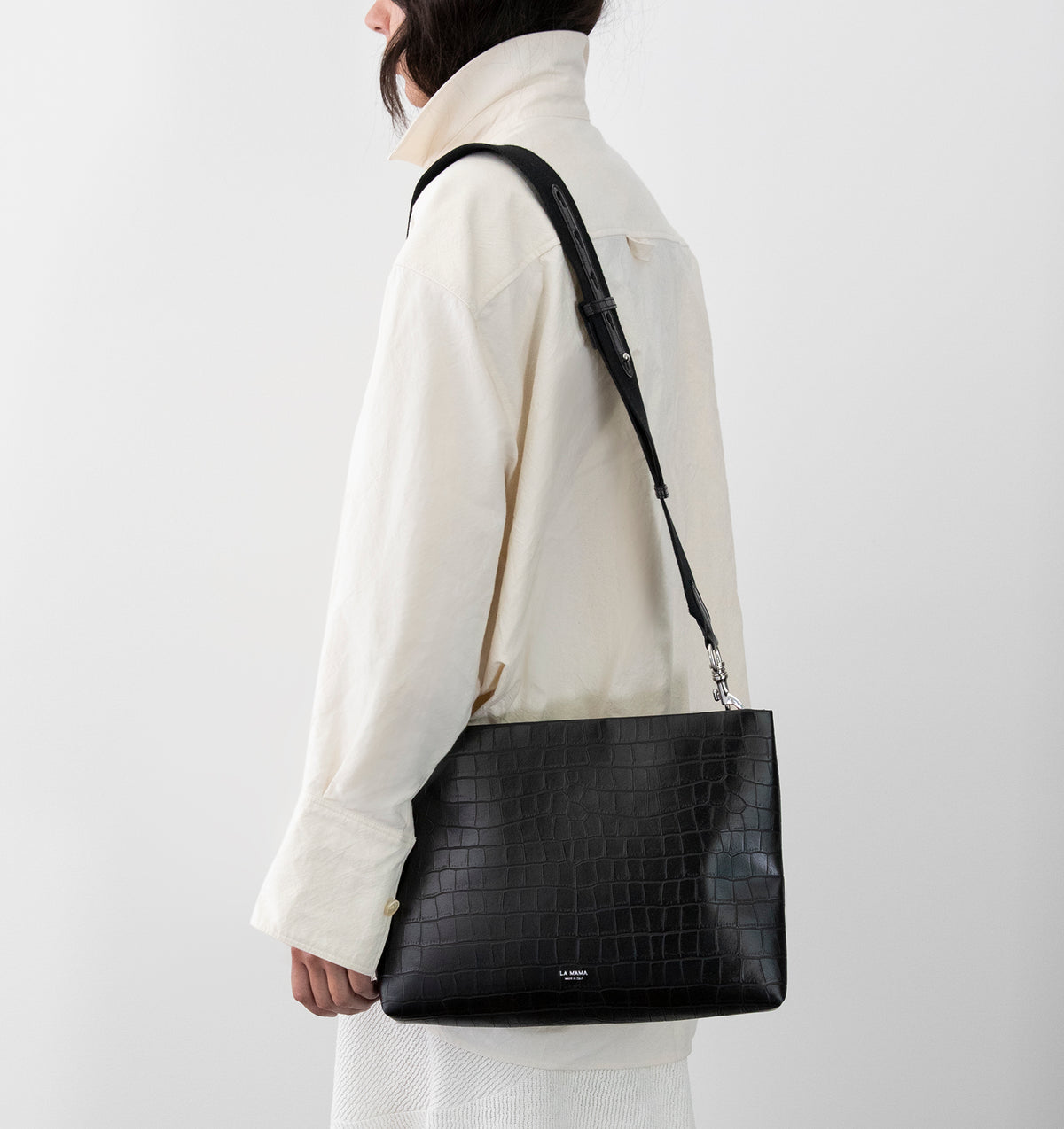 Model wearing the Large Pouch in Black Matte Croco over the shoulder with the Tracolla.