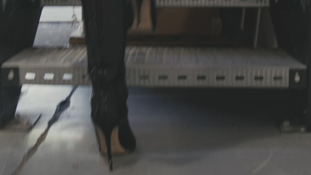 Video of a woman walking in a factory between a LA MAMA LM1 handbag in Black Matte Croco and a LA MAMA LM1 handbag in Black Lacquer Croco.